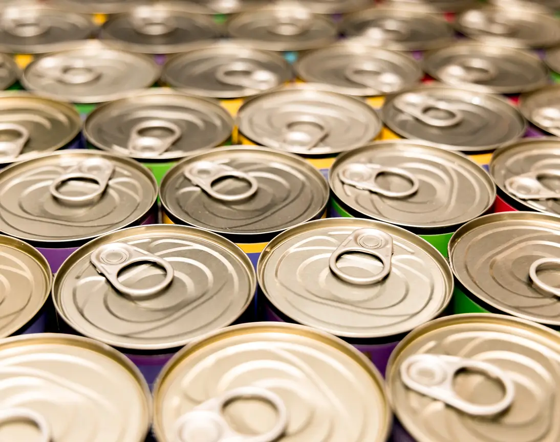 Close-up of unopened beverage cans with pull tabs arranged closely.